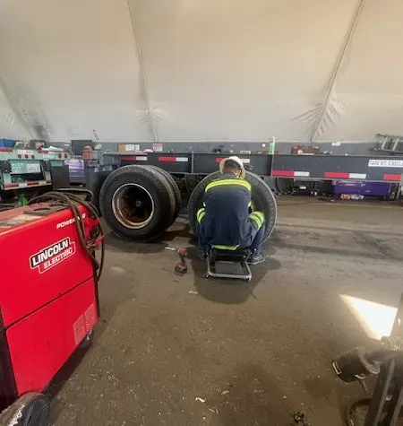 pb worker fixing wheel on trailer