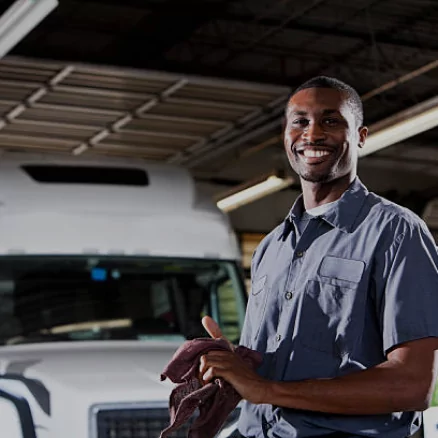 mechanic wiping his hands in front of a white semi truck